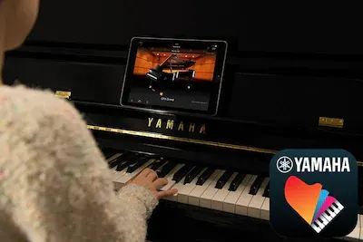 Niña practicando con tablet smart pianist en piano acústico
