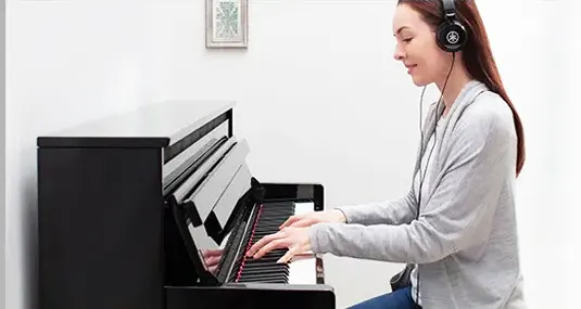 Mujer tocando piano con auriculares estereofónicos