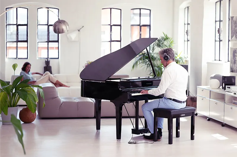 Hombre tocando piano de cola hibrido Clavinova 795GP Negro Pulido