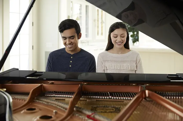 Hombre y mujer pianista tocando piano de cola ecónomico GC1 M de Yamaha