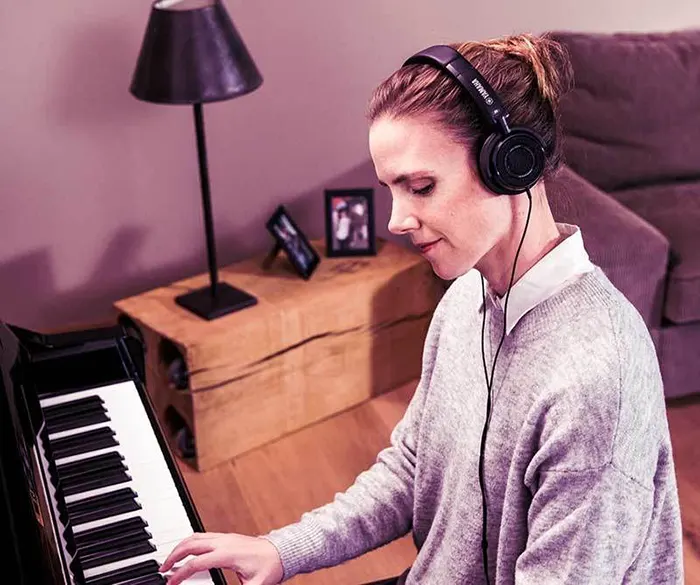 Mujer tocando piano con auriculares