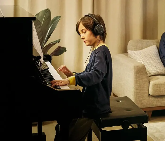 Niño tocando piano Silent de Yamaha con auriculares